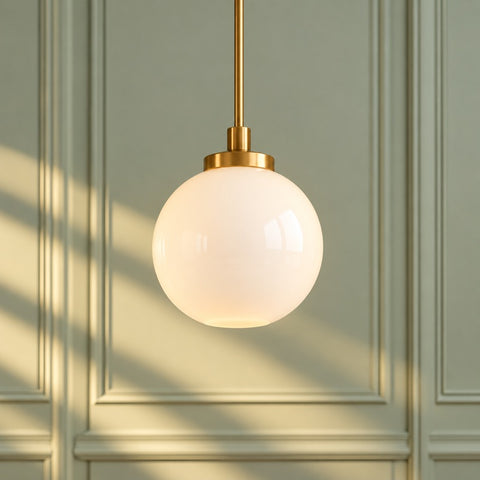 A glowing brass pendant lamp against a sage wall